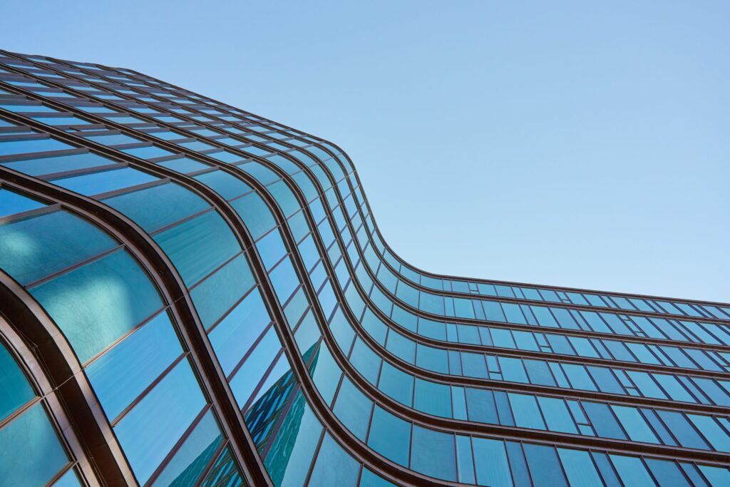 Modern building with curved glass facade reflecting sky.